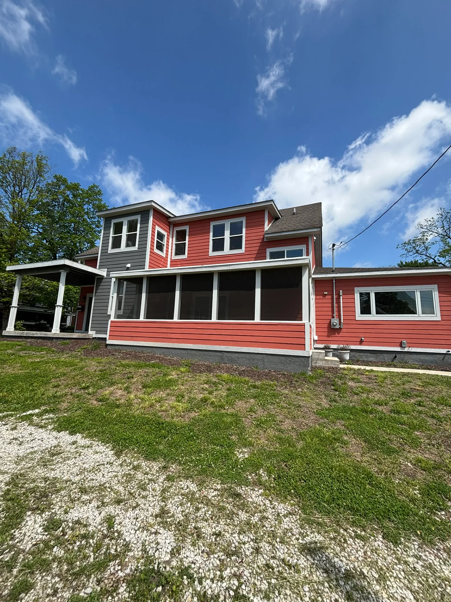 Two-story home with red and gray fiber cement siding, white trim, replacement windows, and screened porch in Indianapolis, IN