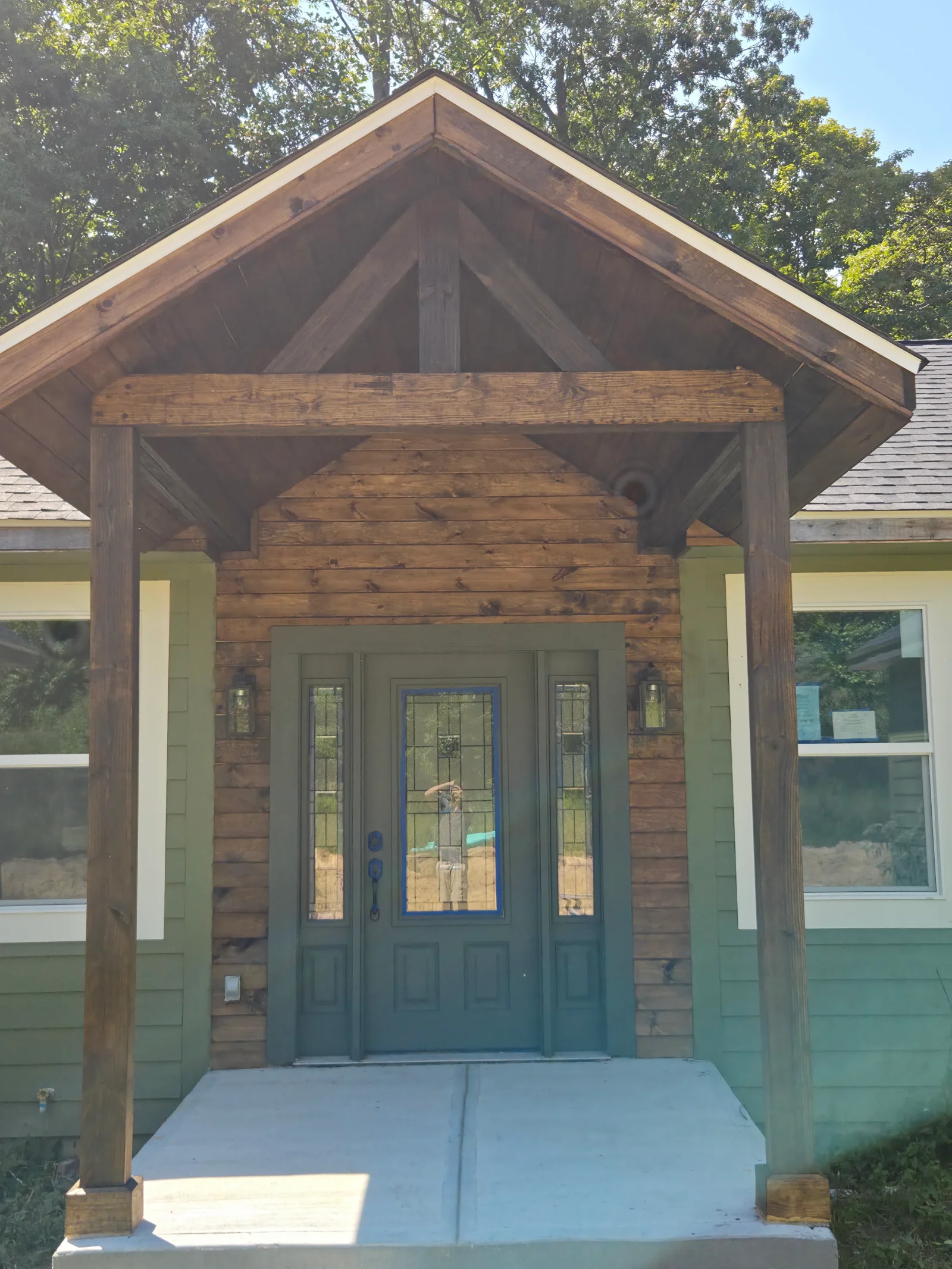 Timber-framed entry portico with log siding, gabled roof, and blue entry door built in Indianapolis, IN