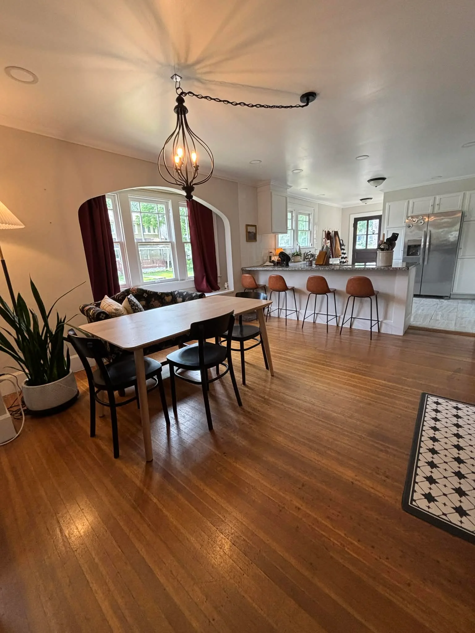 Open kitchen with white cabinetry, hardwood floors, island seating, and dining area in Plainfield, IN