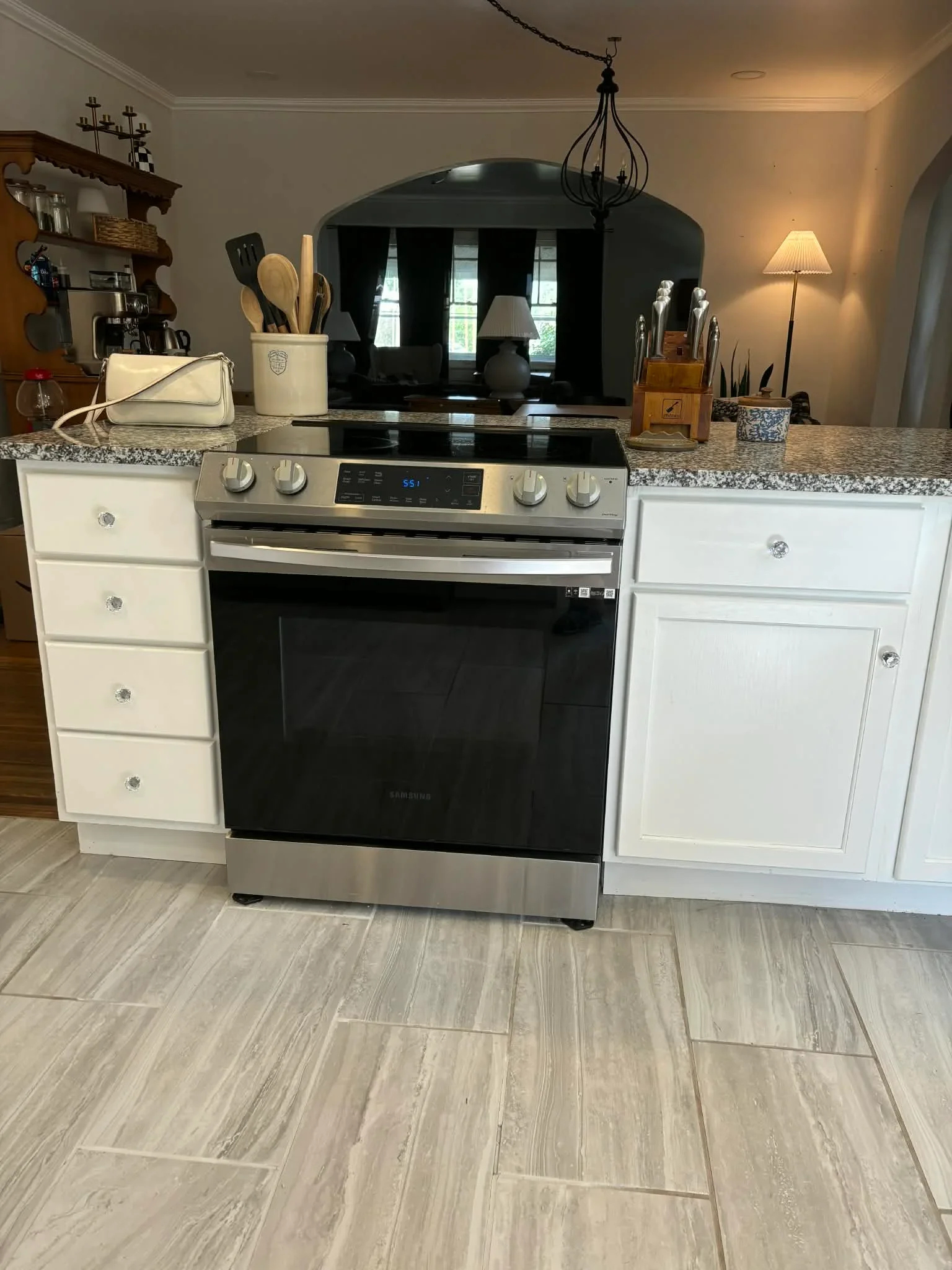 White shaker cabinets, granite countertops, stainless steel range, and wood-look tile flooring in remodeled Indianapolis kitchen