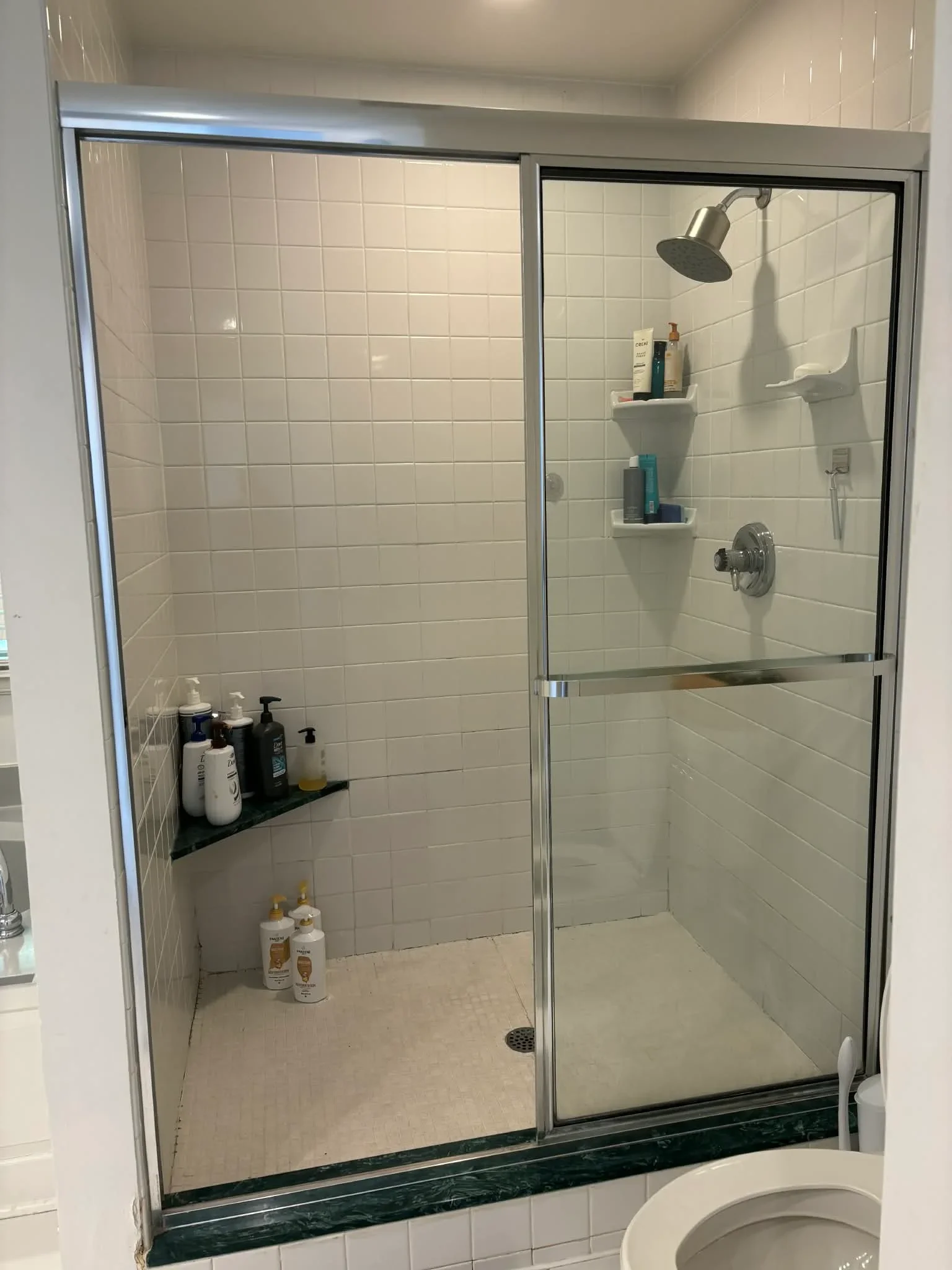 Frameless glass shower with white subway tile walls and integrated shelving installed in Carmel, IN bathroom