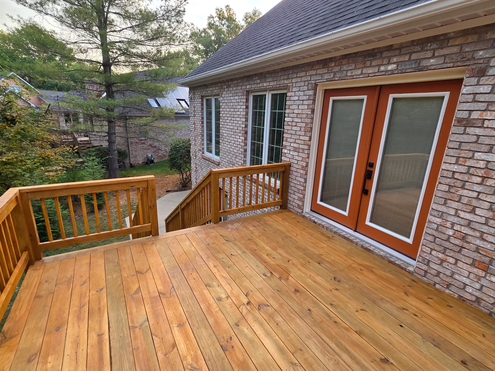 Two-level honey-stained wood deck with custom railings and French door access in Beech Grove, IN