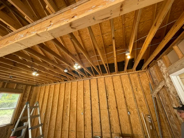 Residential interior framing with lumber joists, wall studs, and recessed lighting rough-in before drywall in Indianapolis, IN