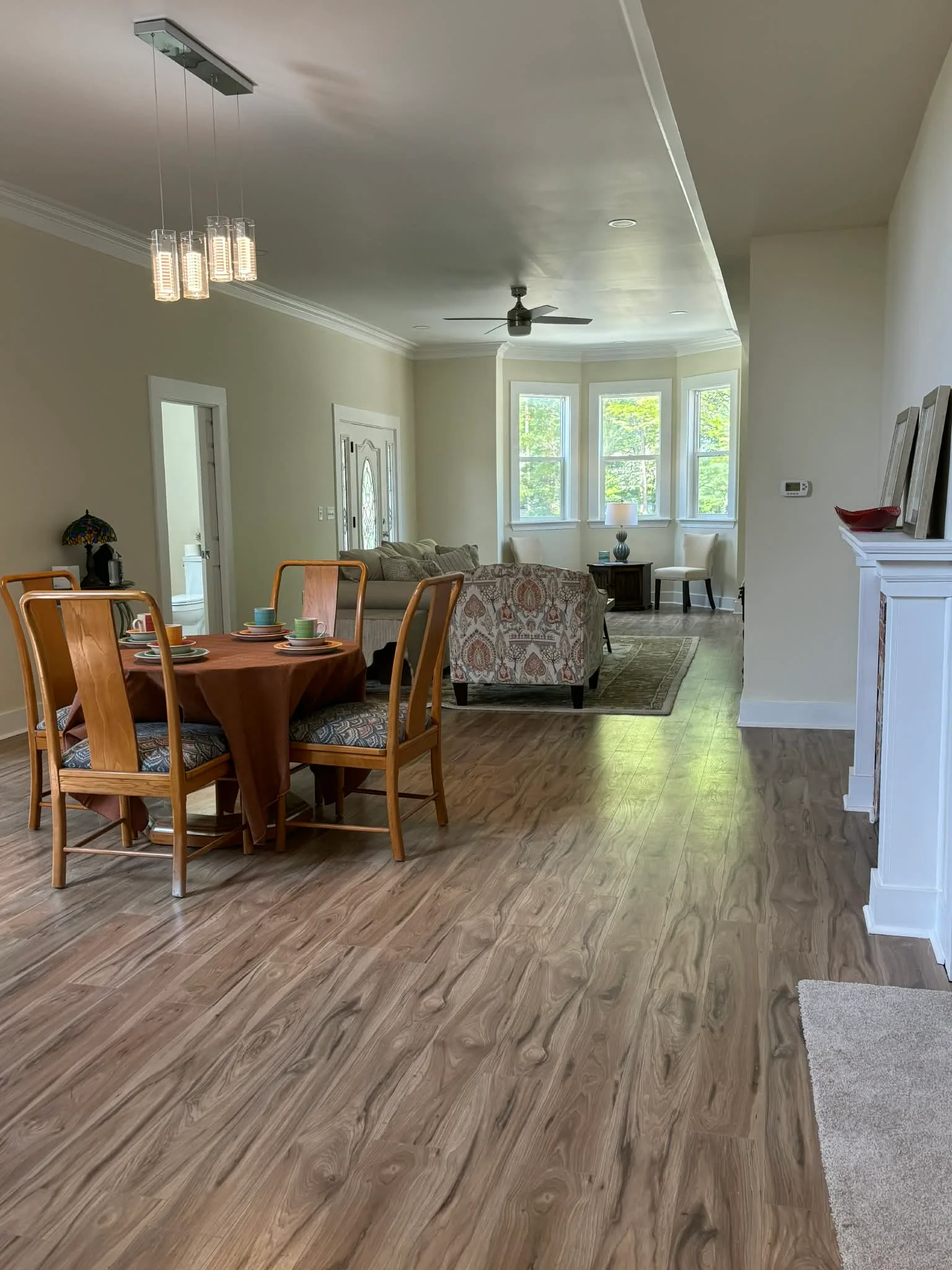 Open concept living room with vinyl plank flooring, crown molding, pendant lighting, and ceiling fan in Mooresville, IN