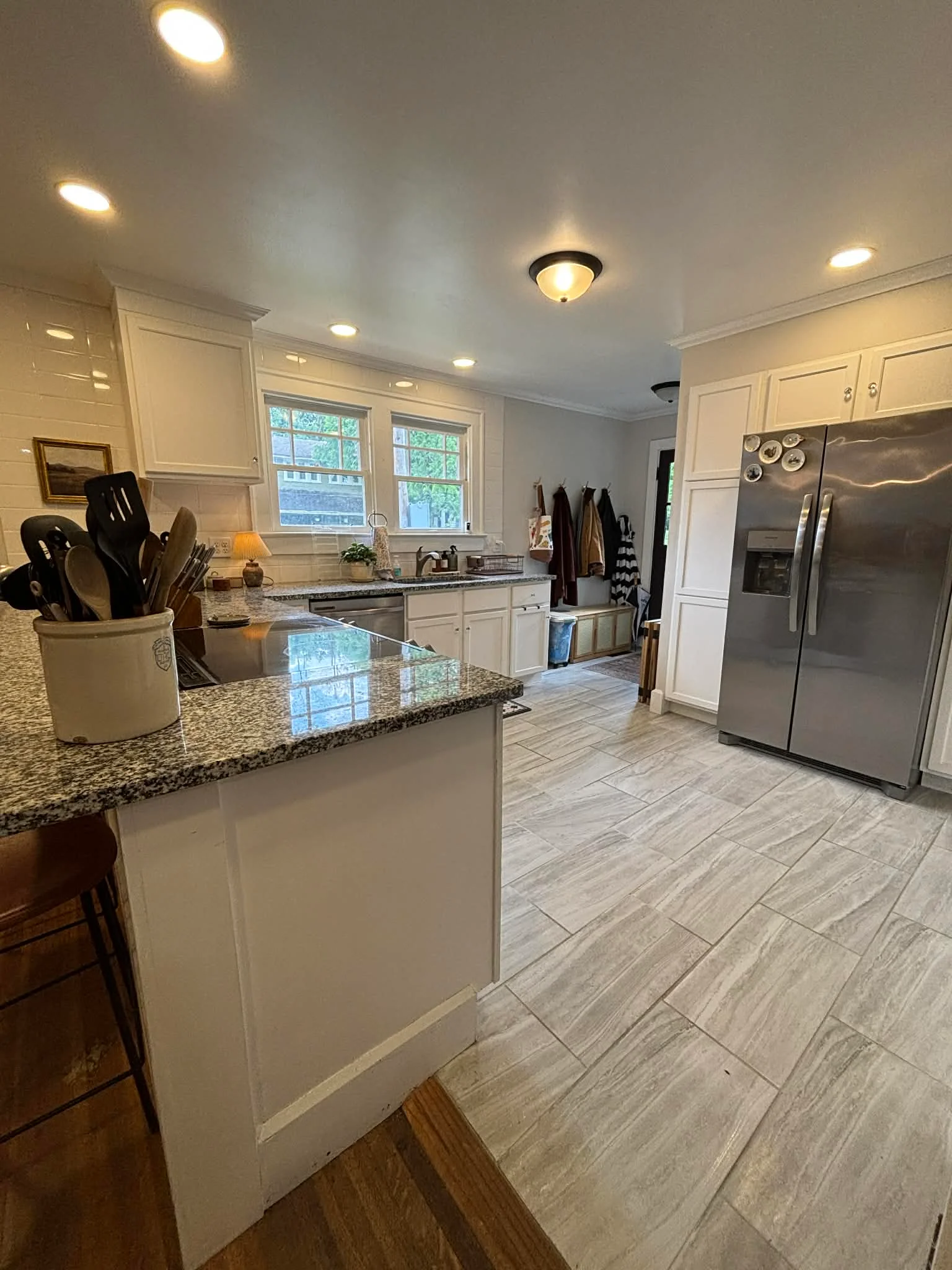 White kitchen with granite island, stainless steel appliances, and wood-look tile flooring in Indianapolis, IN