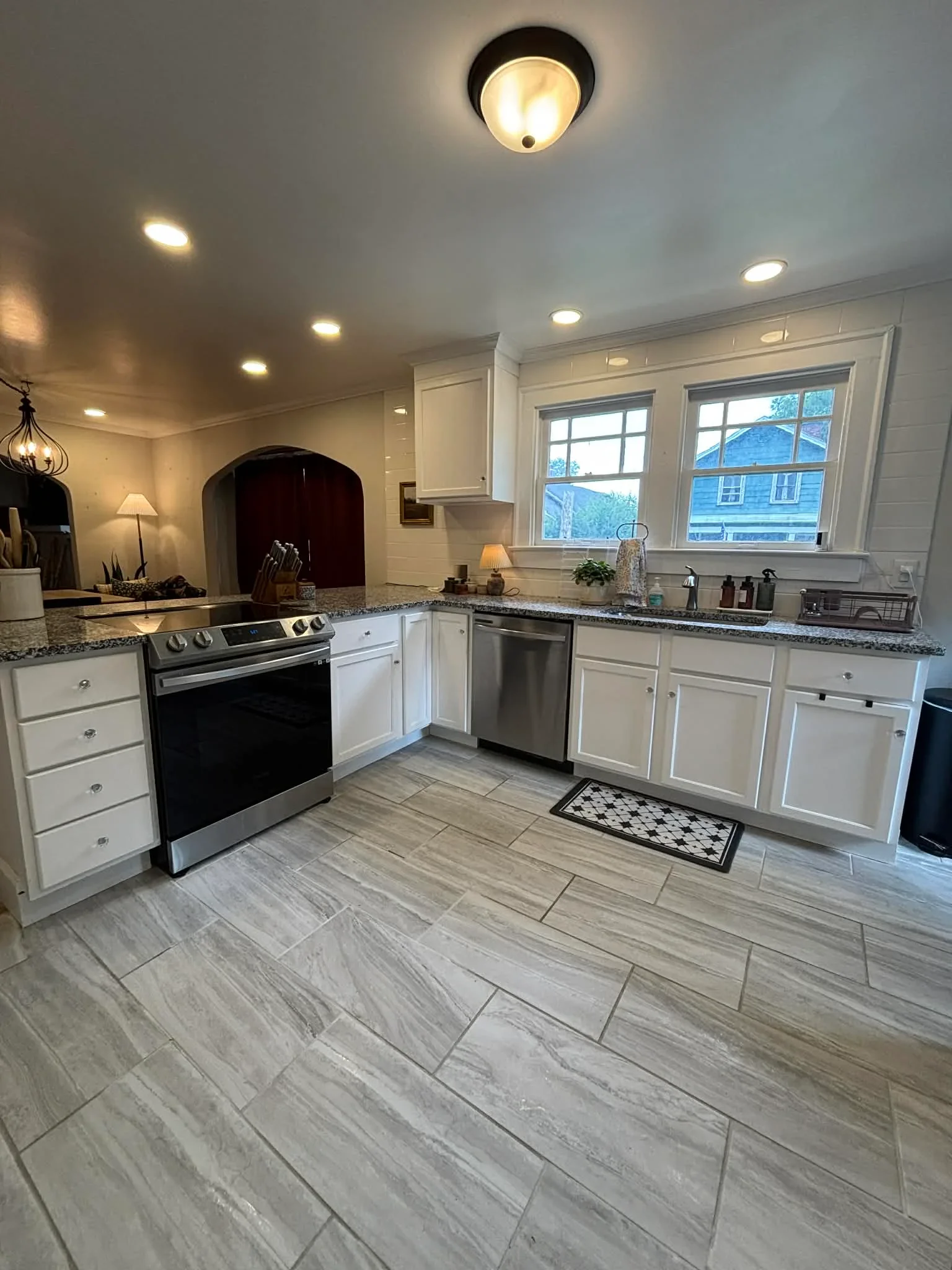 White kitchen with granite counters, stainless steel appliances, and herringbone wood-look tile flooring in Noblesville, IN