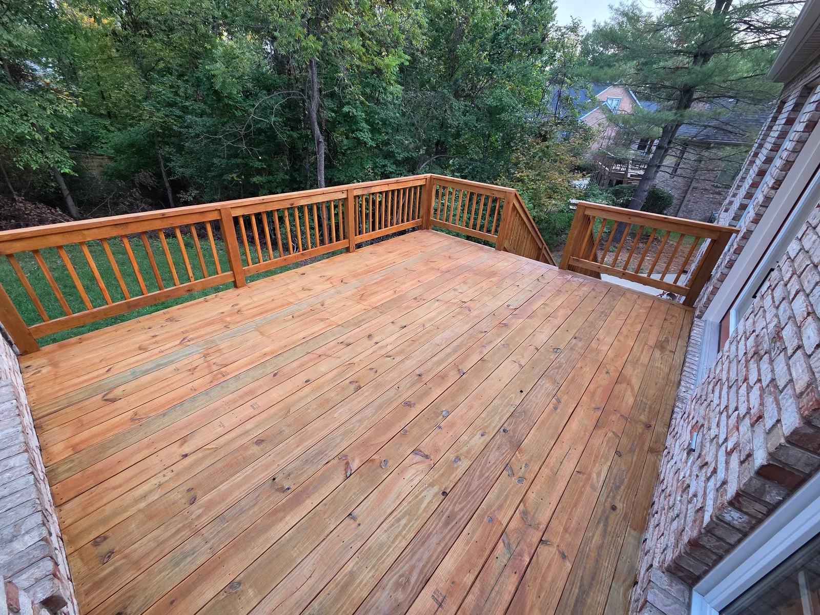 Elevated wood deck with diagonal decking pattern and vertical spindle railings overlooking wooded yard in Fishers, IN